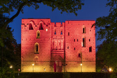 At night, red tones are added to the walls of the ruins.