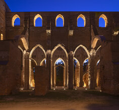 As dawn breaks, warm light spreads up over the ruins from the ground level.